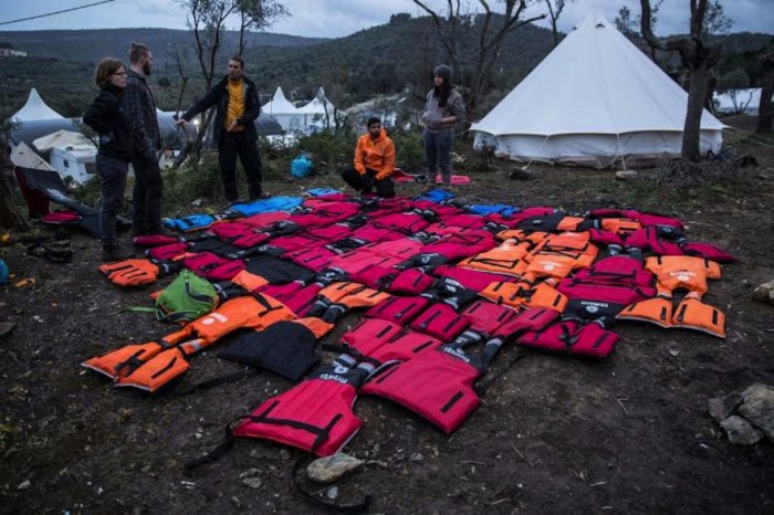 Mads Damgaard Peterson (centre) stands in front of a large mattress made from repurposed life-jackets at Moria refugee registration centre on Lesbos.